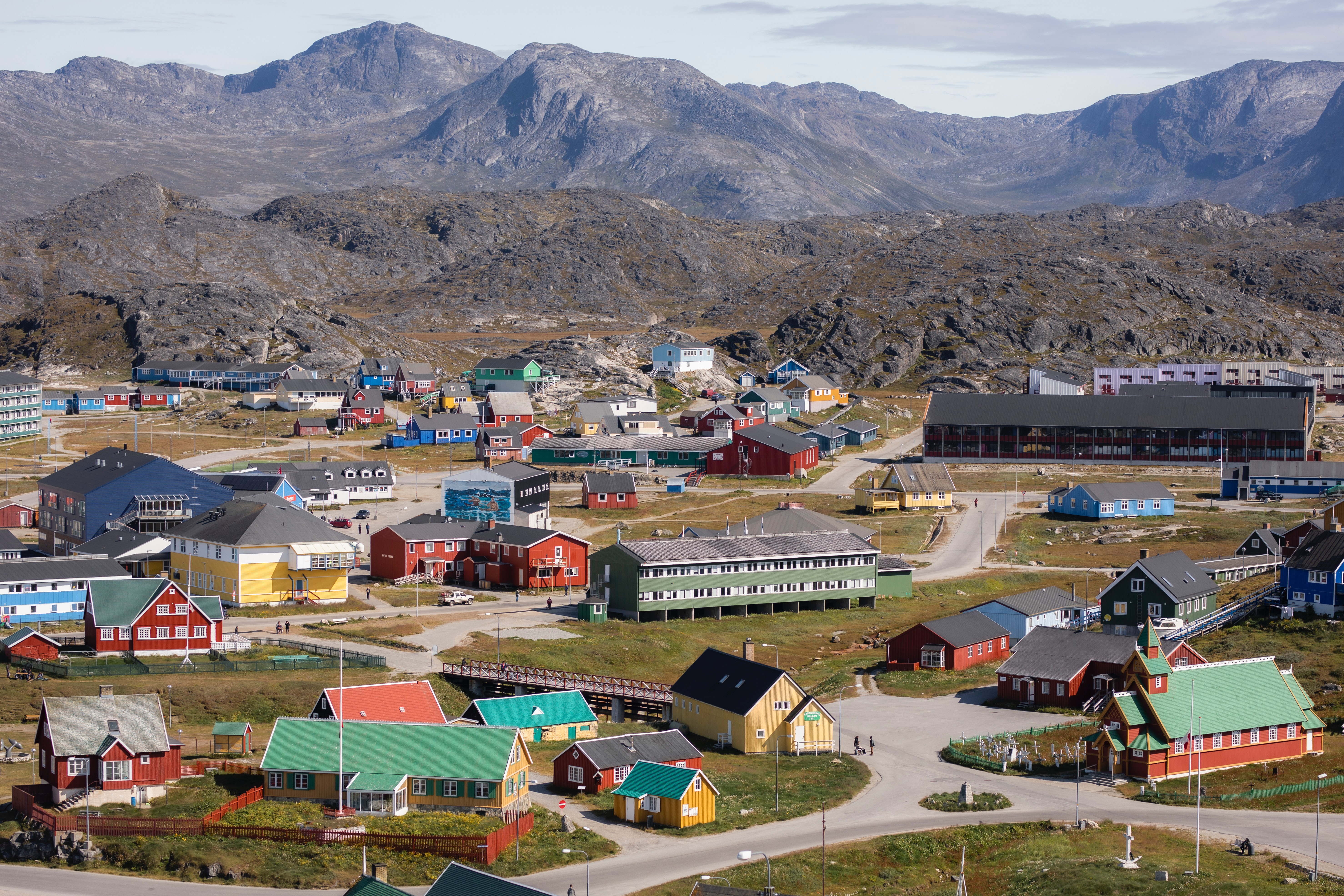Sweeping picture of Nuuk, Greenland, woth mountains in background and coloured houses in foreground.